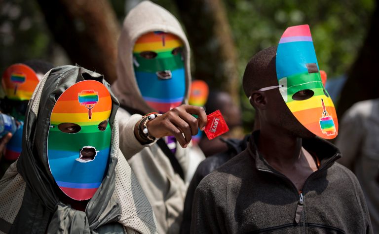 FILE - In this Monday, Feb. 10, 2014 file photo, Kenyan gays and lesbians and others supporting their cause wear masks to preserve their anonymity and one holds out a condom, as they stage a rare protest, against Uganda's increasingly tough stance against homosexuality and in solidarity with their counterparts there, outside the Uganda High Commission in Nairobi, Kenya. Uganda's President Yoweri Museveni is expected to sign Monday, Feb. 24, 2014 a controversial anti-gay bill that allows harsh penalties for homosexual offenses, a bill which rights groups have condemned as draconian in a country where homosexuality is already illegal. (AP Photo/Ben Curtis, File)