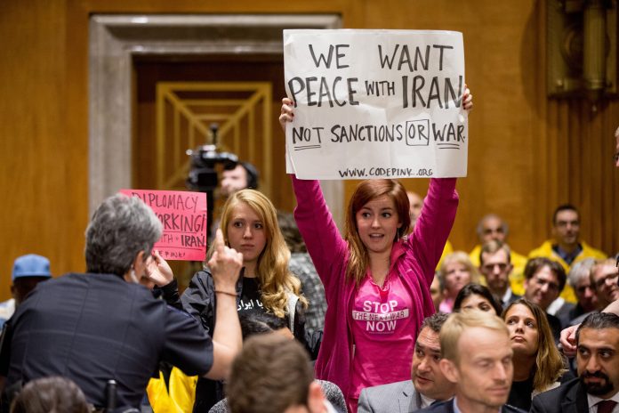 A Capitol Hill police officer asks members of the protest group CodePink to sit down during a Senate Foreign Relations Committee business meeting on Capitol Hill in Washington, Tuesday, April 14, 2015. (AP Photo)Â