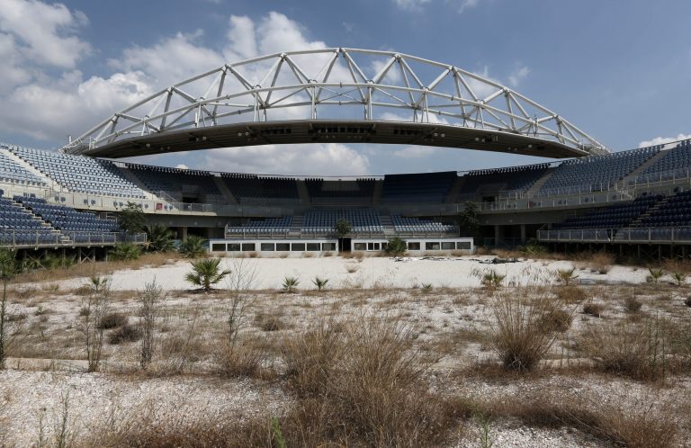 In this Friday, Aug. 8, 2014 photo, the abandoned beach volleyball Olympic venue is seen in Neo Faliro, southern Athens. As Greece groans under a cruel depression, forecast to end this year, the 10-year anniversary once again raises the question of whether the Athens Games were too costly an undertaking for a weak economy. (AP Photo/Thanassis Stavrakis)