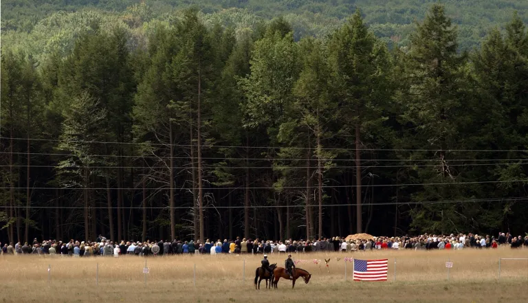 FILE - In this Sept. 11, 2002 file photo police officers patrol the field in front of the area where United Flight 93 crashed as President Bush, accompanied by the first lady Laura Bush, took part in a service for family of the victims of the crash in Shanksville, Pa. The grove of hemlock trees around crash sight is being attacked by an insect that wasnât there 20 years ago, and some scientists say thereâs a link to human-induced climate change. (AP Photo/Julie Jacobson, File)