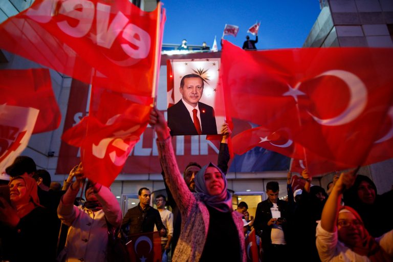 Supporters of Justice and Development party (AK) wave Turkish flags and hold a poster of Turkish President Recep Tayyip Erdogan outside its offices in Istanbul, Sunday, April 16, 2017. (AP Photo/Emrah Gurel)