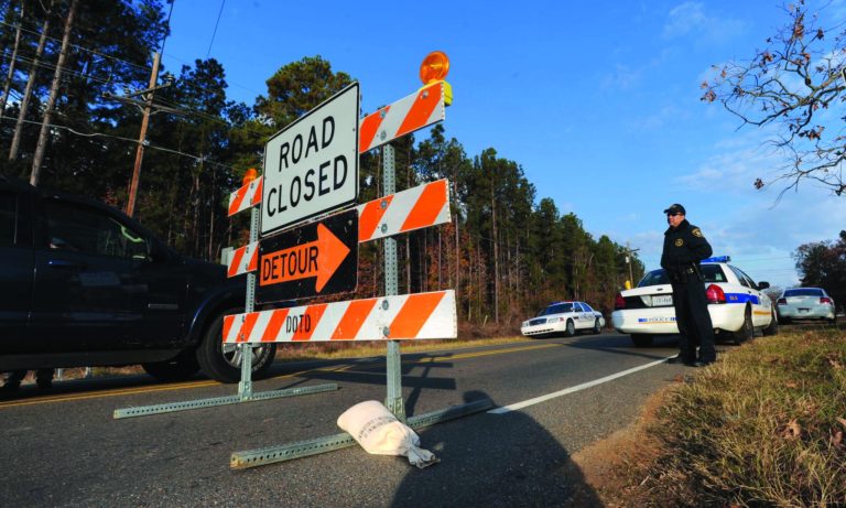 Law enforcement personnel stand at a roadblock along Hwy 163 just south of Doyline, La., Saturday Dec. 1, 2012. Authorities have begun moving 1 million pounds of improperly stored explosive powder to storage bunkers at the Camp Minden industrial site. State investigators found the explosives while inspecting property leased by Explo Systems, where an above-ground storage magazine exploded in October. (AP Photo/The Shreveport Times, Jim Hudelson) MAGS OUT; MANDATORY CREDIT SHREVEPORTTIMES.COM; NO SALES