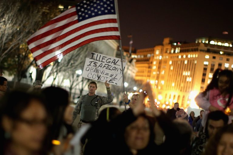 Anti-immigration protesters stand on the periphery of a vigil in support of children fleeing violence in Central American outside the White House November 24, 2014 in Washington, D.C. (Getty Image)