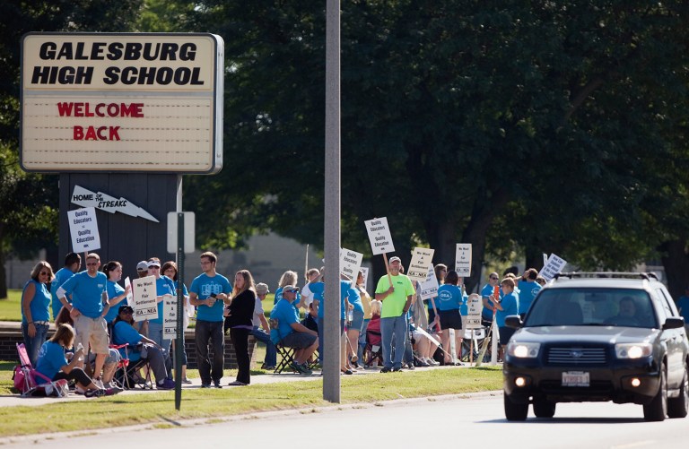 Teachers walk a picket line in front of Galesburg High School in Galesburg, Ill., Wednesday, Aug. 13, 2014, after the Galesburg Education Association turned down a contract offer late Tuesday from District 205 after more than 15 hours of mediation in the past two days. It's the first strike in Galesburg in 37 years. School is scheduled to start Thursday. (AP Photo/The Register-Mail, Steve Davis)