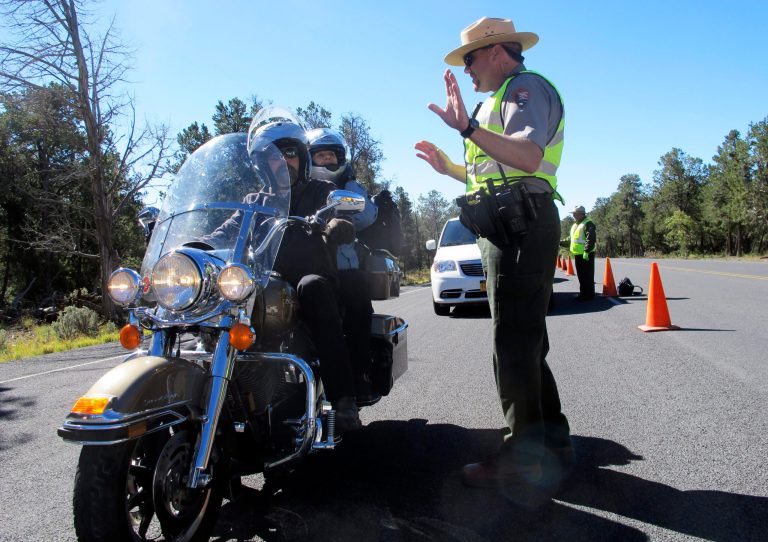 Grand Canyon National Park Ranger Jason Morris talks to people on a motorcycle at the closed park entrance on Thursday in Ariz. More than 400 national parks are closed as Congress remains deadlocked over federal government funding. (AP Photo/Brian Skoloff)