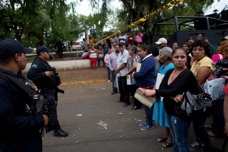 Relatives waiting to be reunited with their children stand behind a police cordon outside The Great Family group home, in Zamora, Michoacan State, Mexico, Wednesday, July 16, 2014. Mexican prosecutors said Wednesday that victims told harrowing tales of sexual abuse, beatings, hunger and filth, in a once well-regarded group home where authorities freed hundreds of adults and children in a raid. (AP Photo/Rebecca Blackwell)