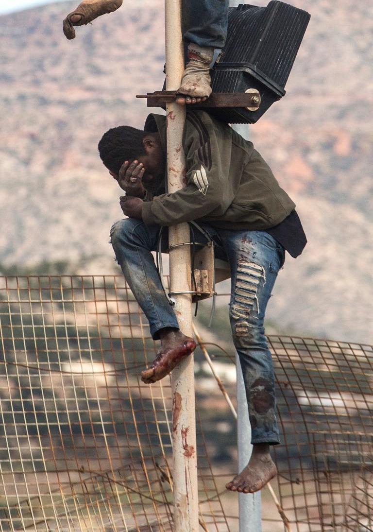 A sub-Saharan migrant sits on top of a pole set in a metallic fence that divides Morocco and the Spanish enclave of Melilla on Thursday April 3, 2014. Spanish and Moroccan police have thwarted a fresh attempt by dozens of African migrants to try to scale border fences to enter the Spanish enclave of Melilla. Thousands of sub-Saharan migrants seeking a better life in Europe are living illegally in Morocco and regularly try to enter Melilla in the hope of later making it to mainland Spain.  (AP Photo / Santi Palacios)