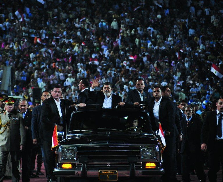 In this image released by the Egyptian Presidency taken on Saturday, Oct. 6, 2012, Egyptian President Mohammed Morsi, waves to the crowd gathered in a stadium upon his arrival for a speech on the 6th of October national holiday marking the 1973 war with Israel in Cairo, Egypt. Morsi boasts of his achievements in his first 100 days in office but sidesteps the key issues in the political transition to democratic rule. (AP Photo/Egyptian Presidency)