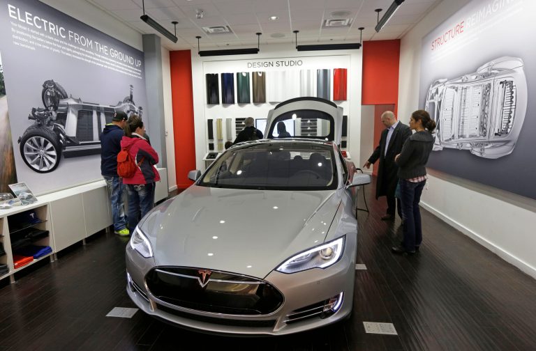 Customers check out a new Tesla all electric car at a Tesla showroom inside the Kenwood Towne Centre in Cincinnati. (AP/Al Behrman)