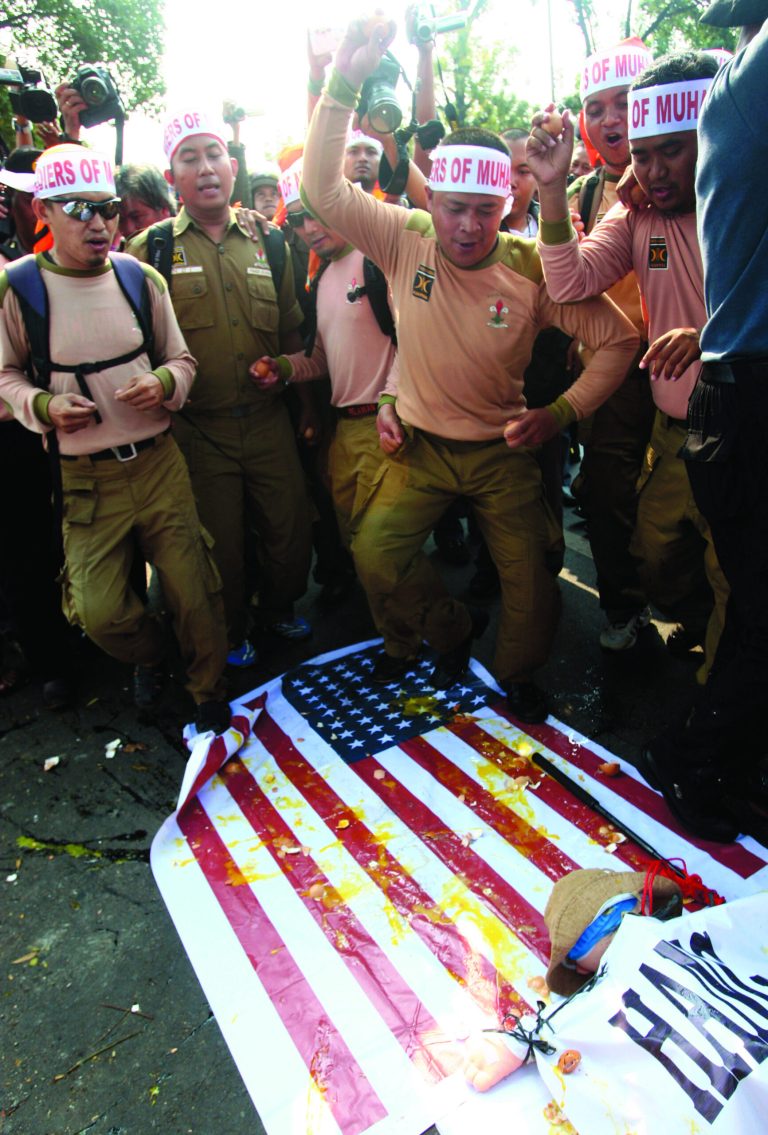Muslim protesters throw eggs at a mock U.S. flag during a protest against American-made film 