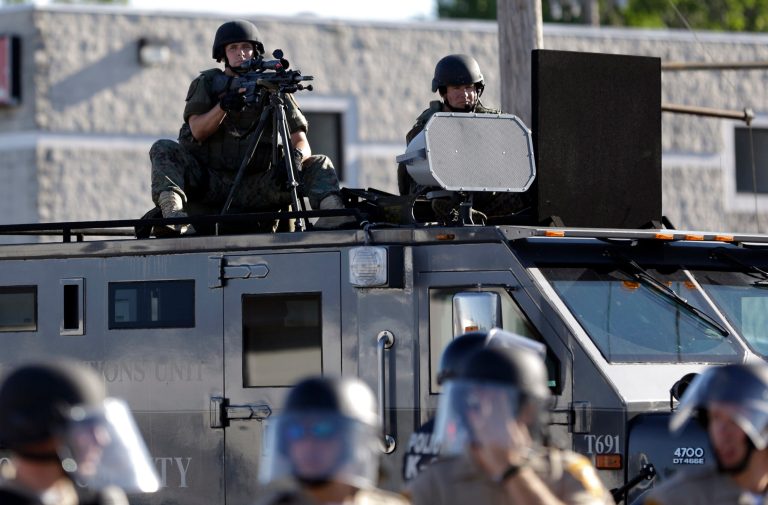 FILE - In this Aug. 9, 2014 file photo, a police tactical team moves in to disperse a group of protesters in Ferguson, Mo. that was sparked after Michael Brown, an unarmed black man was shot and killed by Darren Wilson, a white Ferguson police officer. Senate Majority Whip Richard Durbin of Ill. on Friday asked Defense Secretary Chuck Hagel to review a program that provides high-powered rifles and other surplus military equipment to civilian police departments across the country. (AP Photo/Jeff Roberson, File)