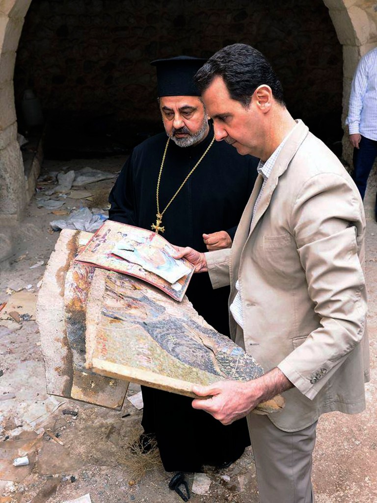In this photo released by the Syrian official news agency SANA, Syrian President Bashar Assad, right, holds a broken religious mosaic, during his visit to the Christian village of Maaloula, near Damascus, Syria, Sunday April, 20, 2014. Assad toured a historic Christian village his forces recently captured from rebels, state media said, as the country's Greek Orthodox Patriarch vowed that Christians in the war-ravaged country 