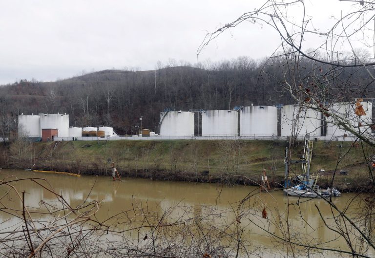 FILE - In this Jan. 13, 2014 file photo, workers, left, inspect an area outside a retaining wall around storage tanks where a chemical leaked into the Elk River at Freedom Industries storage facility in Charleston, W.Va. The powerful chemical industry is putting its lobbying muscle behind legislation that would establish standards for chemicals used in products from household goods to cellphones and plastic water bottles _ but also make it tougher for states to regulate them.   (AP Photo/Steve Helber, File)