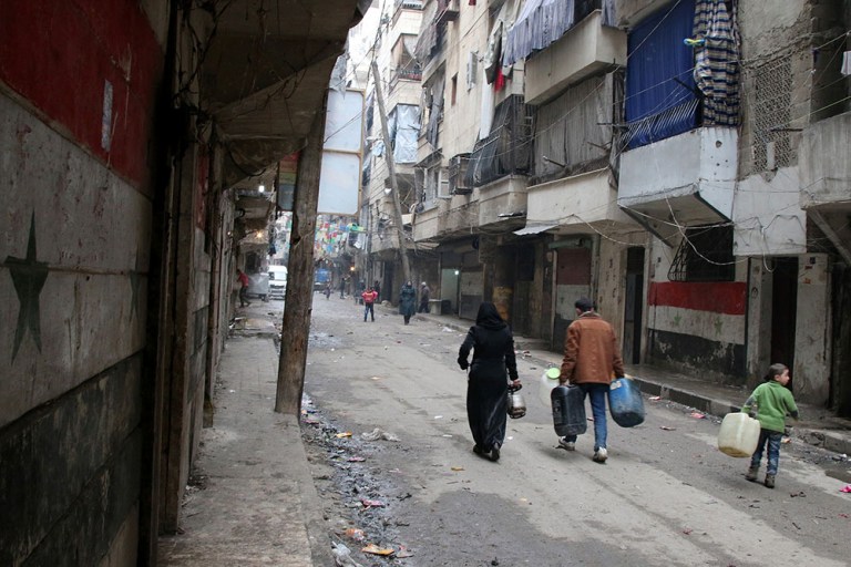 Civilians walk with containers for fuel and water in Aleppo, Syria, Thursday, Feb. 11, 2016. 