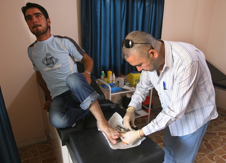 A Syrian doctor, right, who works at a Lebanese medical charity clinic, treats a Syrian man lies on the bed, left, in the northern port city of Tripoli, Lebanon, Wednesday May 21, 2014. Syrian refugees in Lebanon lack access to specialized medical care like dialysis and cancer treatment, forcing some to risk their lives to return to their war-ravaged country for health care, according to a report by Amnesty International released Wednesday. (AP Photo)