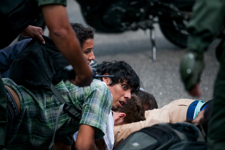 An anti-government demonstrators is held on the ground along with others, as he is detained by the Bolivarian National Guard, during clashes at a protest in Caracas, Venezuela, Wednesday, May 14, 2014. Members of Venezuela's opposition pulled out of crisis negotiations with the government as security forces arrested scores of people in fierce clashes with demonstrators. (AP Photo/Alejandro Cegarra)