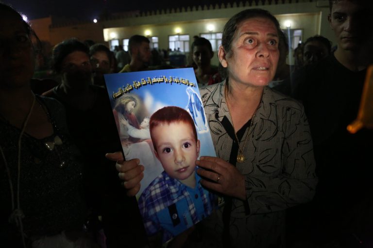 A displaced Iraqi Christian woman holds a picture of her four-year-old relative, David, who was killed by militants, at St. Joseph Church in Irbil, northern Iraq, Thursday, Aug. 7, 2014. Late Wednesday, militants overran a cluster of predominantly Christian villages alongside the country's semi-autonomous Kurdish region, sending tens of thousands of civilians and Kurdish fighters fleeing from the area, several priests in northern Iraq said Thursday. (AP Photo/Khalid Mohammed)