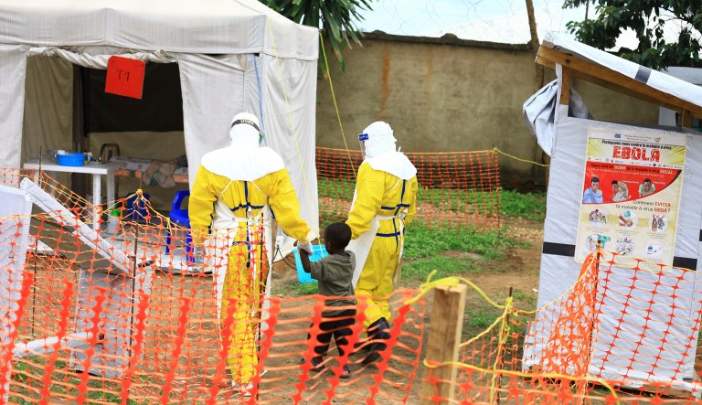 In this photo taken Sunday, Sept 9, 2018, health workers walk with a boy suspected of having the Ebola virus at an Ebola treatment centre in Beni, Eastern Congo. The current Ebola outbreak in northeastern Congo has become a testing ground with one aid group for the first time treating confirmed Ebola victims in individual biosecure units used in emergencies involving highly infectious diseases.