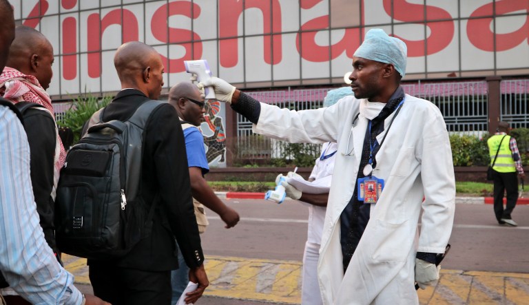 In this photo taken Saturday, June 2, 2018, a health worker checks people's temperatures as they disembark a plane at the airport in Kinshasa, Congo. Hundreds are being vaccinated in Congo's deadly Ebola outbreak but busy taxi drivers who might be ferrying the sick in Mbandaka, an infected city of more than 1 million, argue they are on the front lines as well and should receive the vaccine.