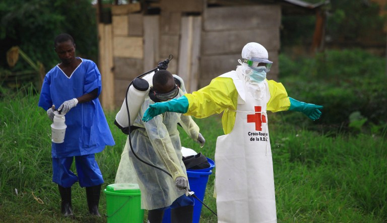 In this photo taken Sunday, Sept 9, 2018, a health worker sprays disinfectant on his colleague after working at an Ebola treatment centre in Beni, Eastern Congo. The current Ebola outbreak in northeastern Congo has become a testing ground with one aid group for the first time treating confirmed Ebola victims in individual biosecure units used in emergencies involving highly infectious diseases.