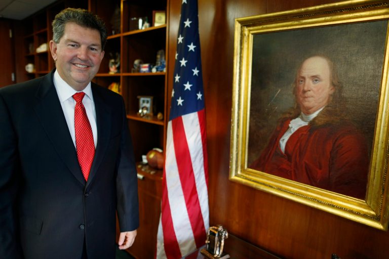   Postmaster General Patrick R. Donahoe poses with next to a portrait of Benjamin Franklin, the first postmaster general, after an interview with the Associated Press at his office at U.S. Postal Service Headquarters in Washington, Thursday, Aug. 1, 2013. Donahoe has a wish list for raising cash for his financially ailing agency. High on it is delivery of beer, wine and spirits. In an interview with The Associated Press, Donahoe also endorsed ending most door-to-door and Saturday mail deliveries as cost-saving measures. (AP Photo/Charles Dharapak)  