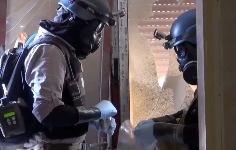 Members of the UN investigation team take samples from the ground in the Damascus countryside of Zamalka, Syria, on Thursday. (AP Photo/Shaam News Network via AP video)