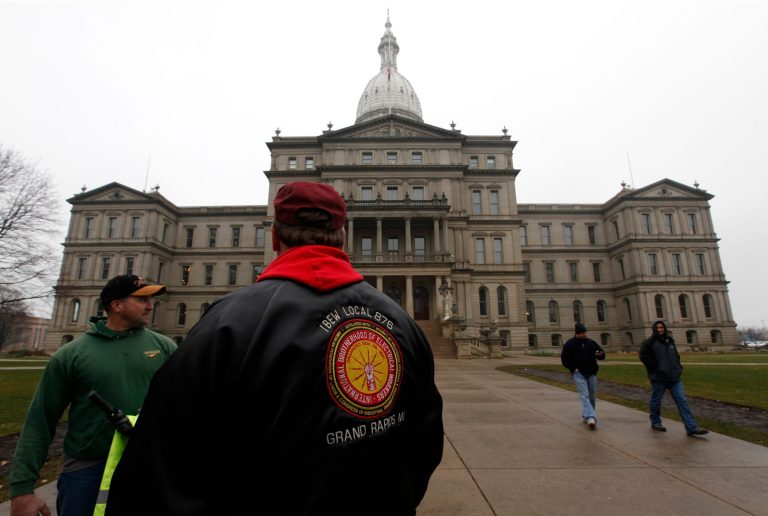   International Brotherhood of Electrical Workers members stand outside the capitol in Lansing, Friday, Dec. 7, 2012. Michigan could become the 24th state with a right-to-work law next week. Rules require a five-day wait before the House and Senate vote on each other's bills; lawmakers are scheduled to reconvene Tuesday and Gov.Snyder has pledged to sign the bills into law. (AP Photo/Paul Sancya)  