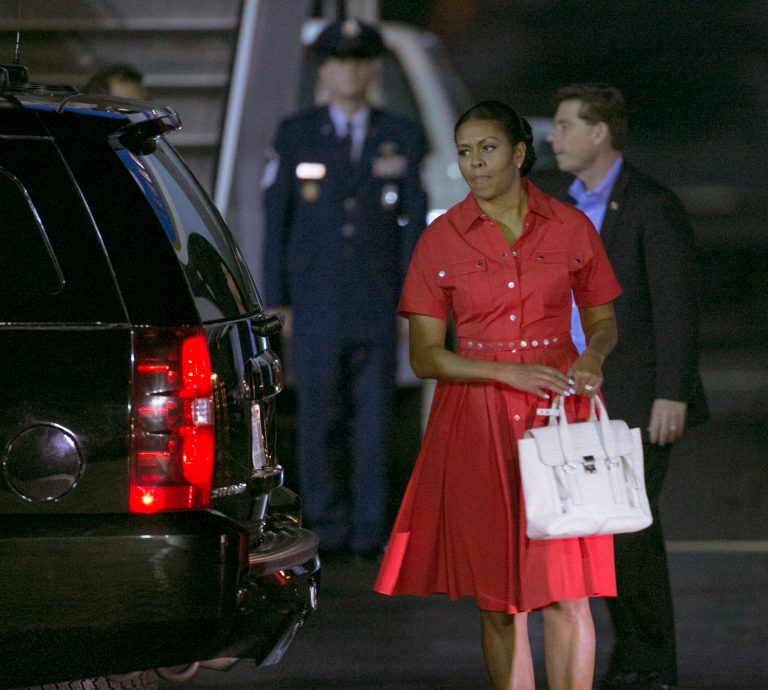U.S. first lady Michelle Obama walks around the presidential limousine upon arriving at Joint Base Pearl Harbor-Hickam, Friday, Dec. 16, 2016, in Honolulu, Hawaii, for her annual family vacation on the island of Oahu. (AP Photo/Marco Garcia)