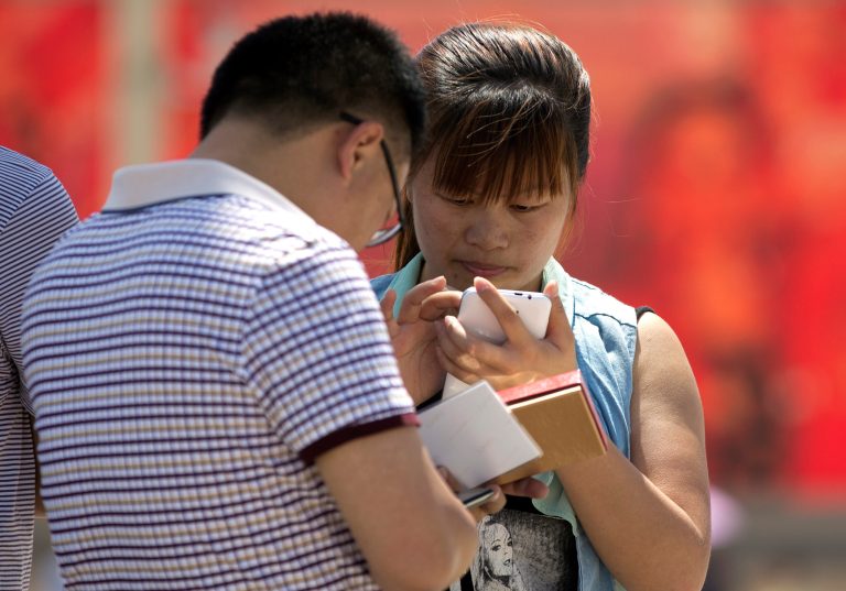 Chinese people use their smartphone on Tiananmen Square in Beijing, China Wednesday, May 28, 2014. China is targeting popular smartphone-based instant messaging services in a month-long campaign to crack down on the spreading of rumors and what it calls 