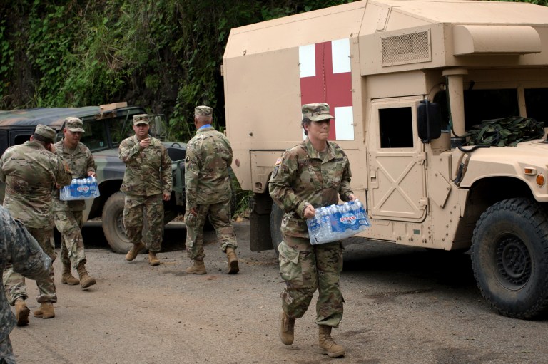 Soldiers assigned to the 1st Mission Support Command, U.S. Army Reserve, move bottled water while working to clear roads of debris near Adjuntas, Puerto Rico, on Oct. 7. (Alex Flynn/Bloomberg)