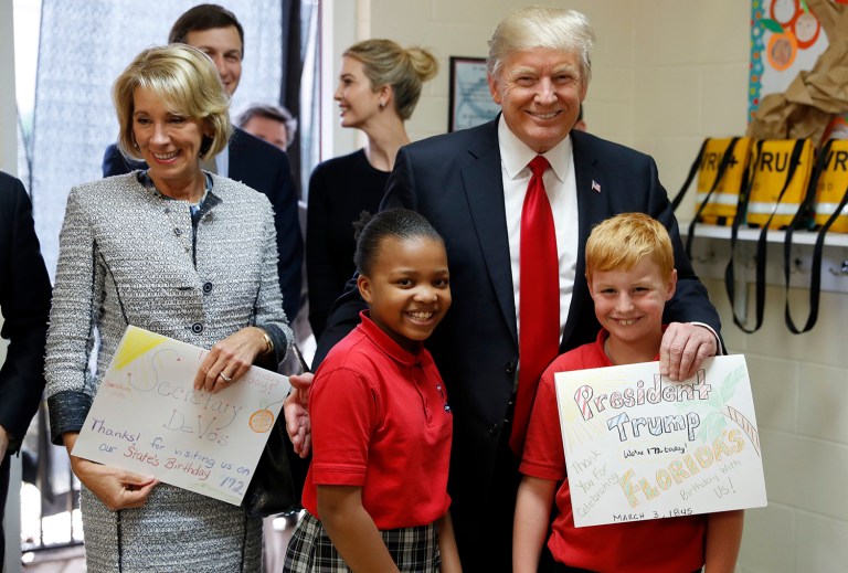 President Trump and Education Secretary Betsy DeVos pose with fourth graders Janayah Chatelier, 10, left, Landon Fritz, 10, after they received cards from the children, during a tour of Saint Andrew Catholic School on Friday in Orlando. (AP Photo/Alex Brandon)