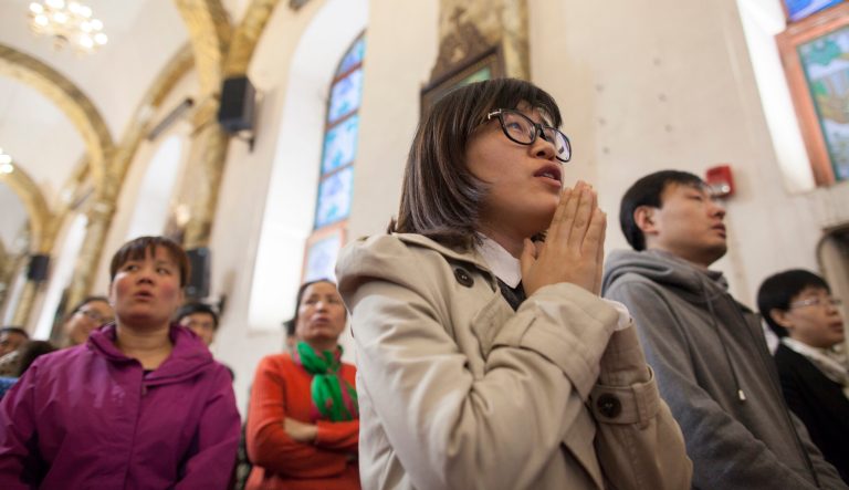 Beijing, China - Min Weiqing, a twenty-seven year old e-commerce marketer, worshipping in a packed Cathedral of the Immaculate Conception.