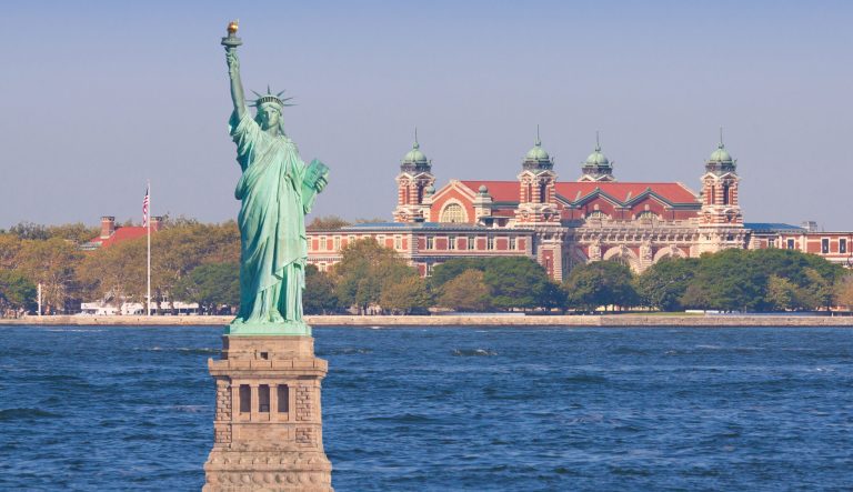 Statue of Liberty with Ellis Island in background, New York City. More than 12 million immigrants entered America through the golden door of Ellis Island. 