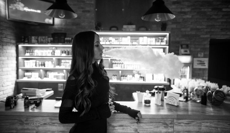 Vaping teenager. Young girl smoking an electronic cigarette in vape bar.