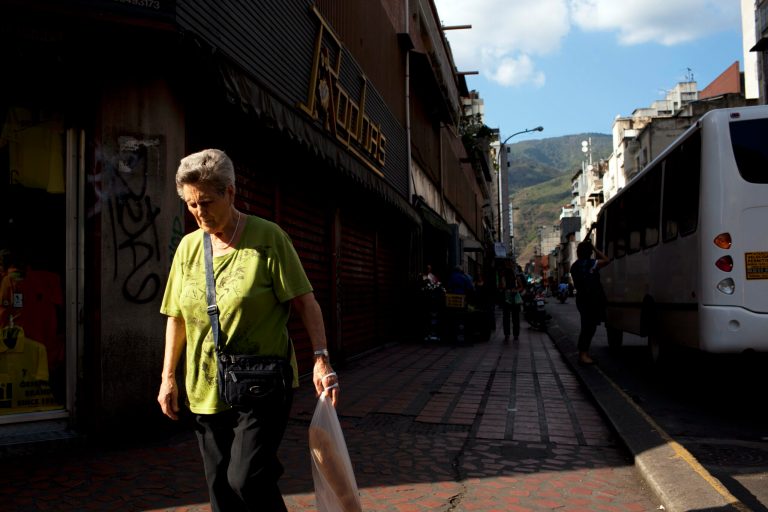 FILE - In this Feb. 20, 2014 file photo, a woman walks downtown after buying bread in Caracas, Venezuela. Venezuelans may soon have to scan their fingers to buy bread at the supermarket. President Nicolas Maduro announced late Wednesday, Aug. 20, 2014 a new, mandatory grocery fingerprinting system to combat food shortages. In the spring, Venezuela tried a similar system in government-run supermarkets on a voluntary basis. (AP Photo/Rodrigo Abd, File)