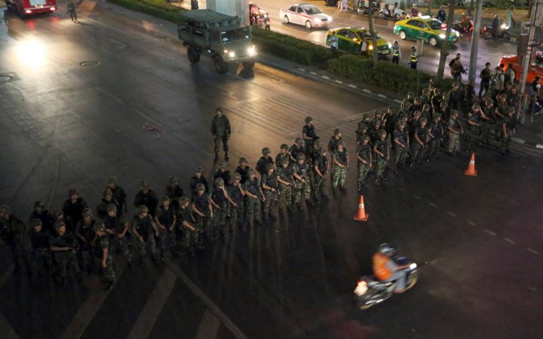 A motorcyclist rides past Thai soldiers blocking the road to prevent activists and pro-government protesters from gathering to protest against the coup in downtown Bangkok, Thailand Friday, May 23, 2014. Ousted members of Thailand's former government turned themselves in to the country's new military junta Friday, as soldiers forcefully dispersed hundreds of anti-coup activists who defied a ban on large-scale gatherings to protest the army's seizure of power. (AP Photo/Apichart Weerawong)