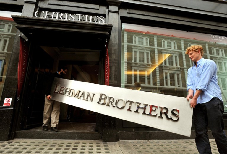 Christie's employees walk into the auction rooms with the main sign from the Lehman Brothers office collection during a photo call at Christie's in west London. (Press Association via AP Images)