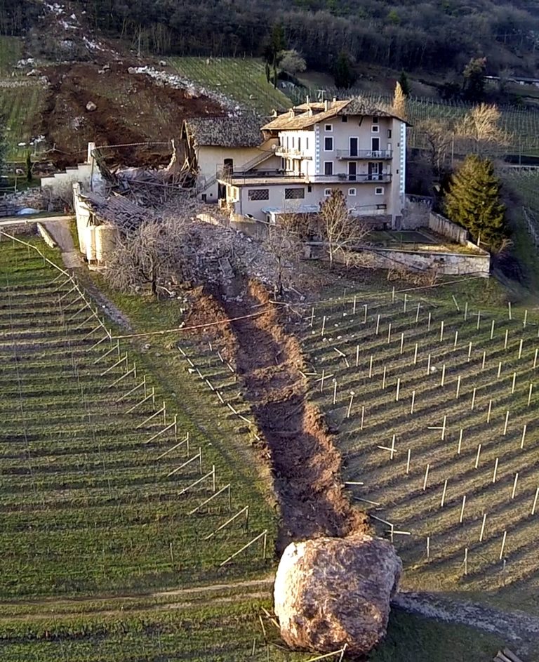 In this photo provided by Tareom.com Thursday, Jan. 30, 2014, and taken on Jan. 23, 2014, a huge boulder is seen after it missed a farm house by less than a meter, destroying the barn, and stopped in the vineyard, while a second giant boulder, which detached during the same landslide on Jan. 21, 2014, stopped next to the house, in Ronchi di Termeno, in Northern Italy. According to reports, the Trebo family living there was unharmed in the landslide. (AP Photo/Markus Hell, Tareom.com, ho)