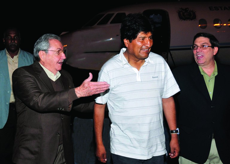 In this picture released by the Cuban newspaper Juventud Revelde, Bolivia's President Evo Morales, center, is welcomed by Cuba's President Raul Castro, left, and Cuba's Foreign Minister Bruno Rodriguez at the Jose Marti international airport in Havana, Cuba, early Sunday, Dec. 23, 2012. Evo Morales is in Cuba to visit Venezuela's President Hugo Chavez, who is recovering from a surgery, his fourth operation related to his pelvic cancer since June 2011. (AP Photo/Juventud Revelde, Estudios Revolucion)