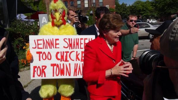 Sen. Jeanne Shaheen campaigns in New Hampshire as a man in a chicken costume stands behind her. (Photo courtesy New Hampshire Republican State Committee)