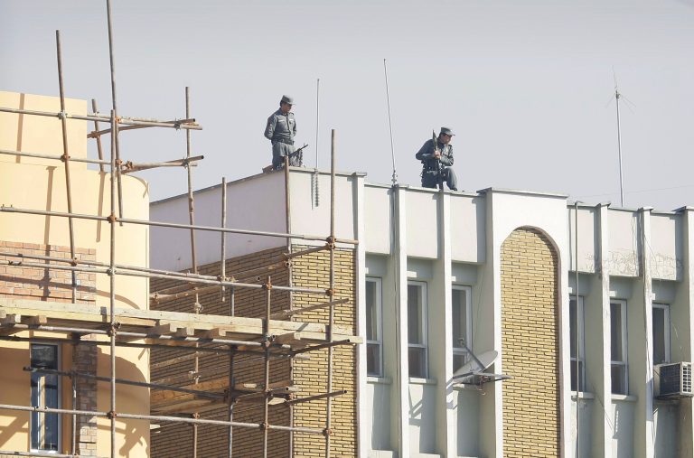   Afghan policemen watching down from top of the Kabul police headquarters, following the killing of an American advisor in Kabul, Afghanistan, Monday, Dec. 24, 2012. An Afghan policewoman killed an American adviser at the Kabul police headquarters on Monday, a senior Afghan police official said. (AP Photo/Musadeq Sadeq)  