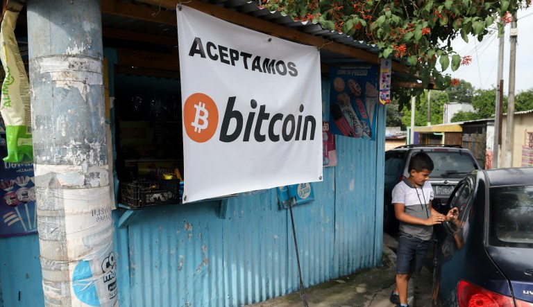 A Salvadoran boy stands next to a car as he waits in front of a small shop that accepts Bitcoin in San Salvador, El Salvador, Saturday, Sept. 4, 2021. The government of President Nayib Bukele, will inaugurate on September the Chivo ATM network, which will be used as the digital wallet of the cryptocurrency, pushing El Salvador as the first country to adopt BitCoin as a legal currency. 