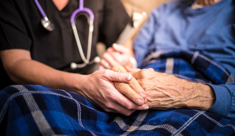 A stock photo of a hospice nurse visiting an elderly male patient who is receiving hospice/palliative care.