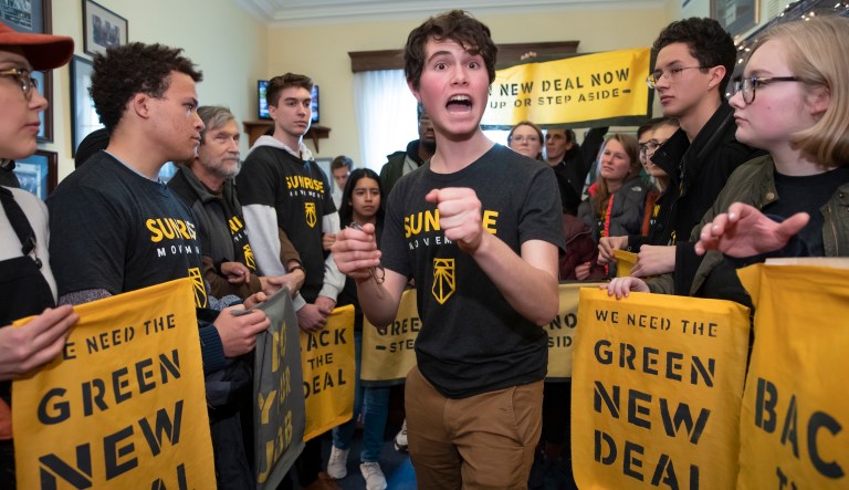 Jeremy Ornstein of Watertown, Mass., cheers on fellow environmental activists as they occupy the office of Rep. Steny Hoyer, D-Md., the incoming majority leader, as they try to pressure Democratic support for a sweeping agenda to fight climate change, on Capitol Hill in Washington, Monday, Dec. 10, 2018.