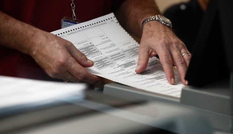 A worker loads a ballot into a machine at the Broward County Supervisor of Elections office during a recount on Tuesday, Nov. 13, 2018, in Lauderhill, Fla.