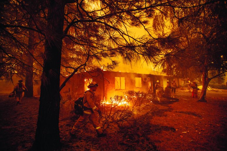 FILE - In this Friday, Nov. 9, 2018, file photo firefighters work to keep flames from spreading through the Shadowbrook apartment complex as a wildfire burns through Paradise, Calif. Authorities say the fire is 95 percent contained Thursday, Nov. 22. The blaze that started Nov. 8 leveled Paradise, killing multiple people and destroyed more than 13,000 homes. (AP Photo/Noah Berger, File)