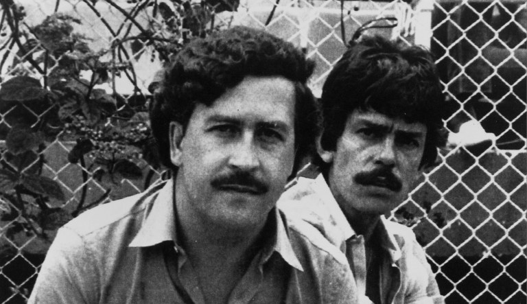 Pablo Escobar, left, 41-year-old billionaire leader of the Medellin drug cartel, poses at a soccer game in Medellin, Colombia, in 1983.  At right is an unidentified bodyguard. 
