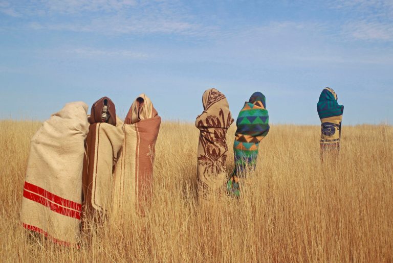 FILE - In this file photo taken Saturday, June 30, 2013  Xhosa boy's stand in a field as they undergo traditional Xhosa male circumcision ceremonies into manhood in Qunu, South Africa. This month, as happens annually in South Africa, youths in some rural areas will head to secluded huts for circumcision rituals meant to usher them into manhood. Officials hope to prevent another wave of injuries and deaths triggered by factors including infections and the tight binding of penis wounds, which cuts off blood supply, as well as sleep deprivation, exposure to winter cold and other harsh conditions. (AP Photo/Schalk van Zuydam, File)