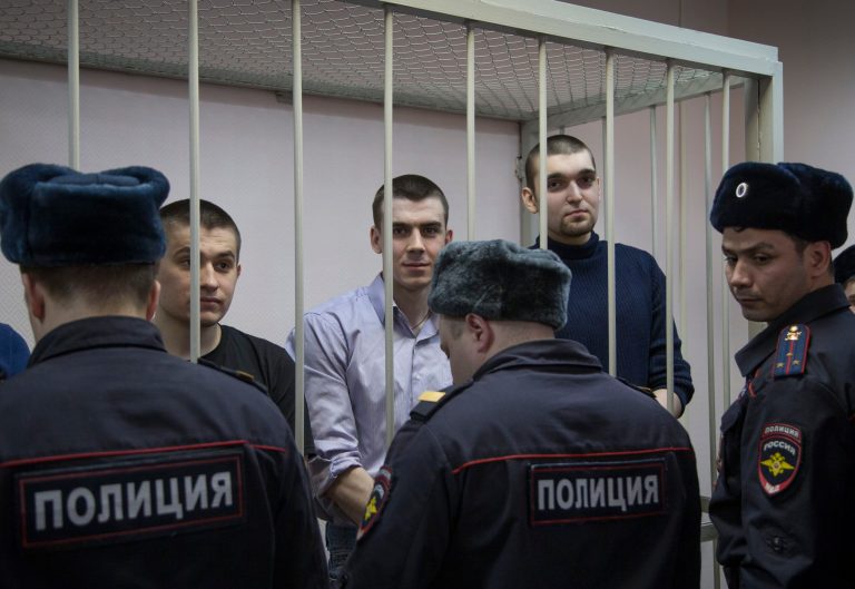 Defendants stand in a glass cage during a trial in Zamoskvoretsky District Court in Moscow, Russia, Friday, Feb. 21, 2014. The defendants face trial for their role in a protest in Moscow on May 6, 2012 that ended in violent clashes with police. (AP Photo/Alexander Zemlianichenko)
