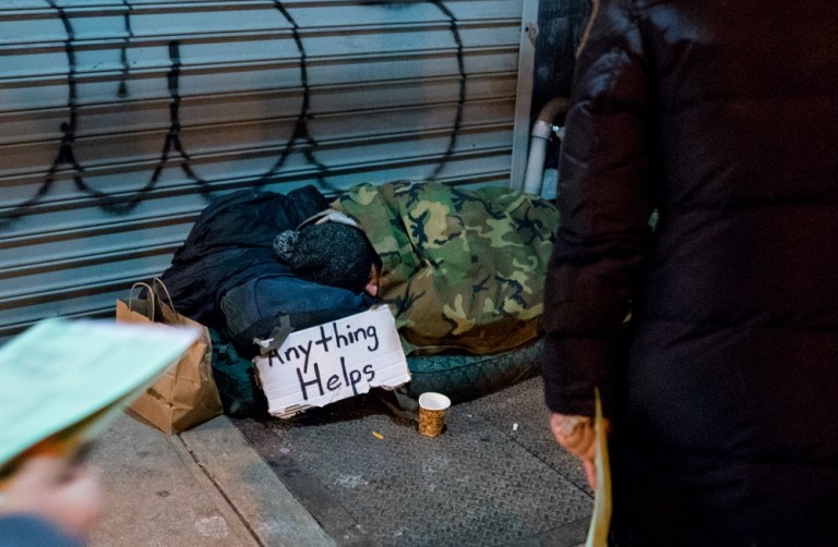 People working with The Robin Hood Foundation, an organization that helps the poor, approach a homeless person sleeping on the sidewalk in an effort to count and conduct a brief survey of the homeless on the streets of New York early Tuesday, Feb. 9, 2016. Hundreds of people fanned out across the city to conduct the survey just after midnight. (AP Photo/Craig Ruttle)